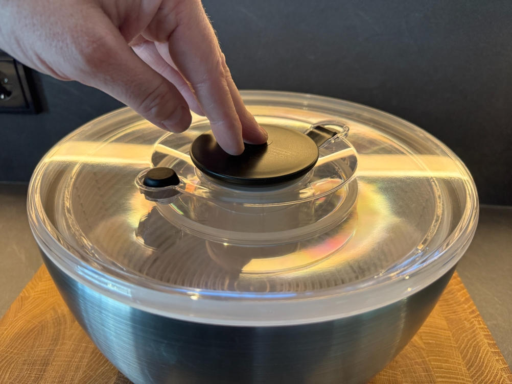 Hand drückt auf Salatschleuder OXO 1071497