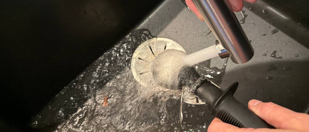 Der Oxo-Eisportionierer wird unter fließendem Wasser gereinigt