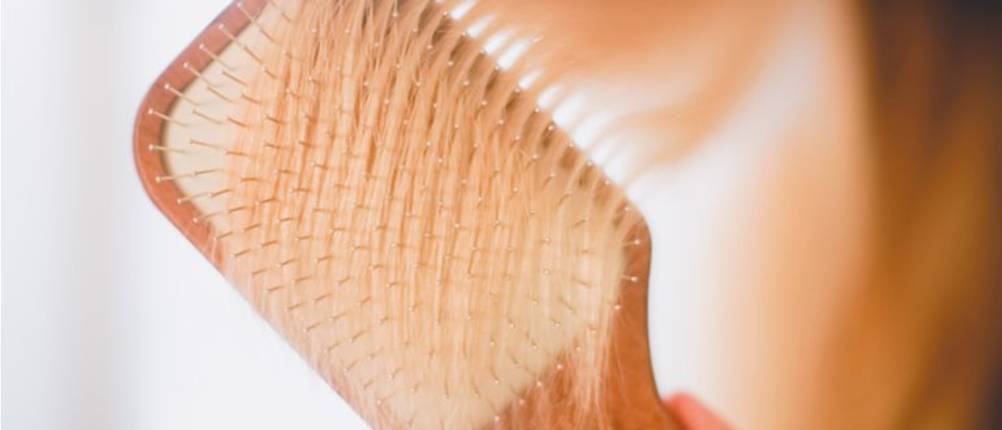 eine Bürste kämmt blondes Haar