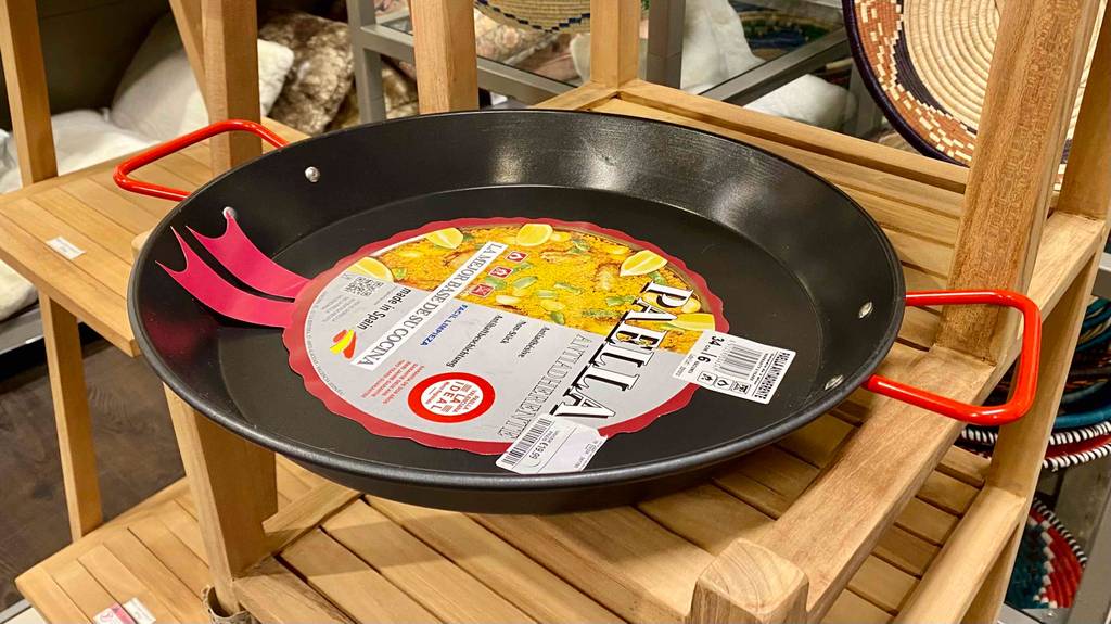 Eine getestete Paella-Pfanne befindet sich in einem Holzregal. 