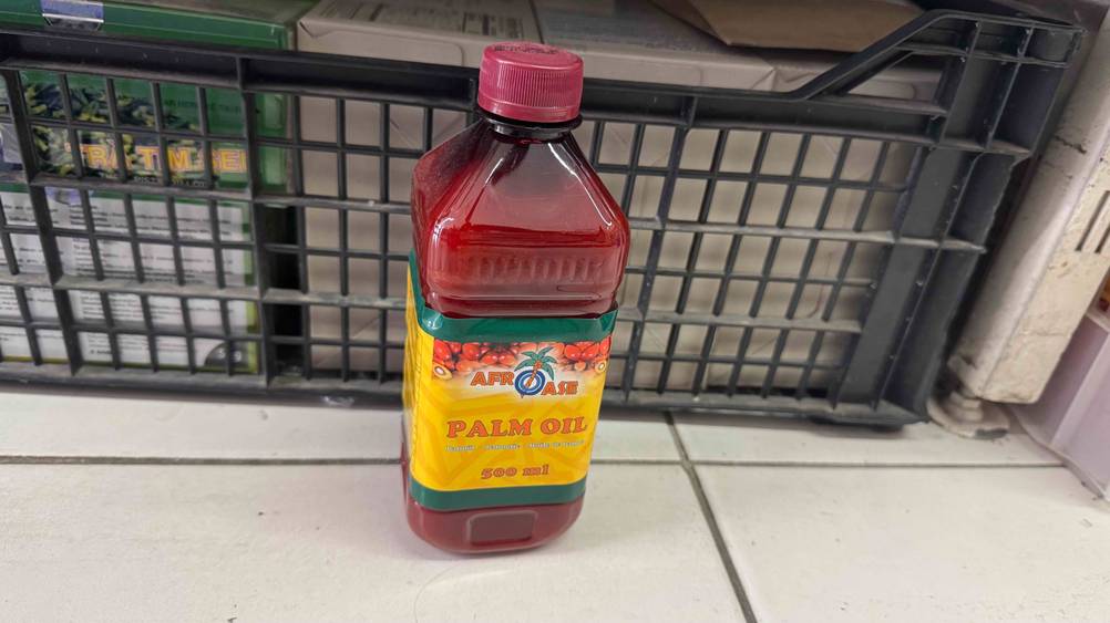 Eine Flasche des Palmöls im Test auf einer hellen Fläche vor einem Plastikkorb.