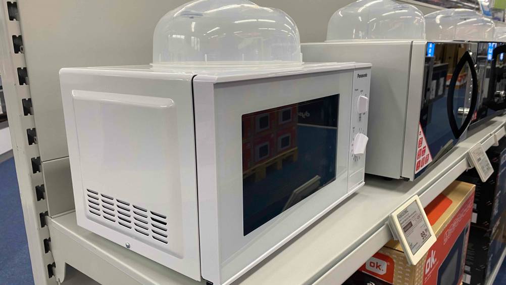 Auf einem Kaufhausregal befindet sich eine getestete Mikrowelle von der Marke Panasonic.