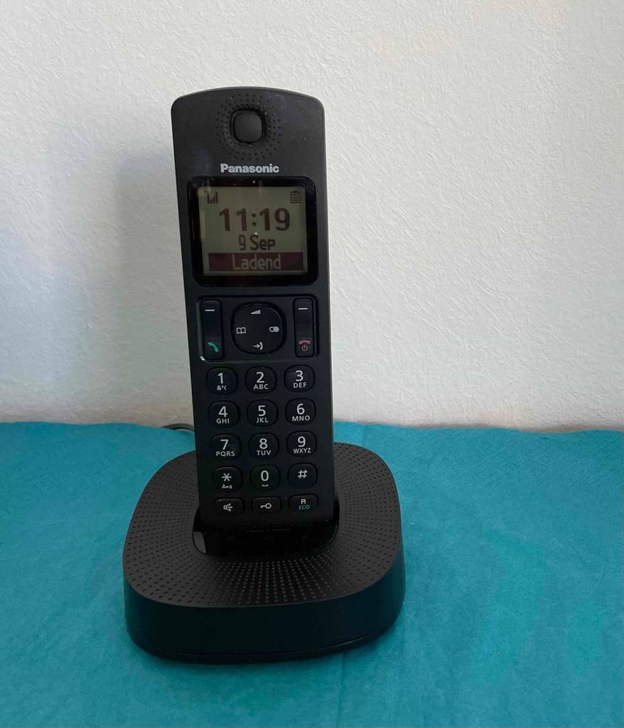 Ein getestetes schnurloses Telefon der Marke Panasonic steht ladend auf seiner Basis-Station.
