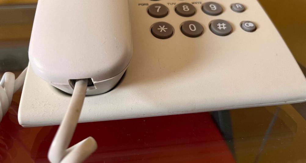Nahaufnahme des im Hörer eingesteckten Kabels eines weißen, getesteten Schnurtelefons der Marke Panasonic.