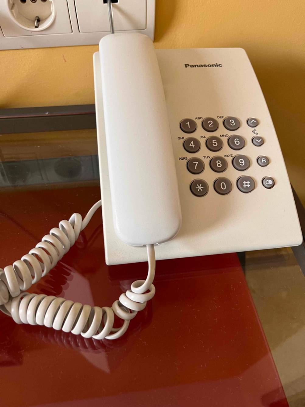 Im Test: ein Schnurtelefon der Marke Panasonic in Weiß steht auf einem Glastisch.