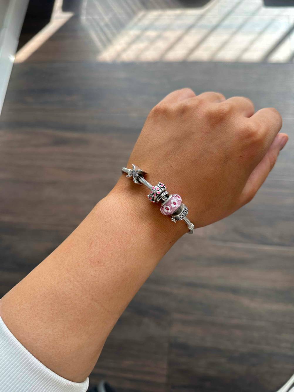 An einem Handgelenk befindet sich ein getestetes Pandora-Armband.