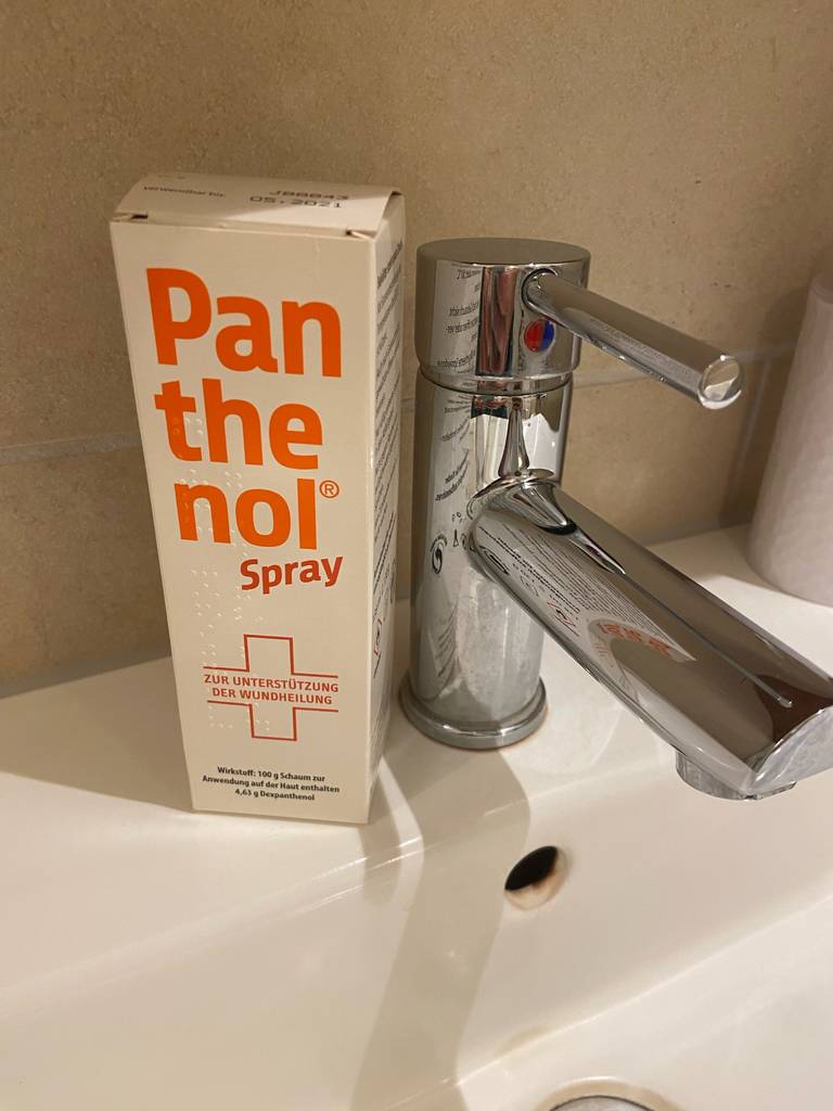 Panthenol-Spray-Test: Die Originalverpackung steht auf einem Waschbecken neben dem Hahn.