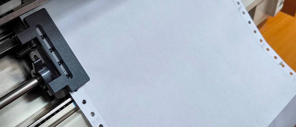 Nadeldrucker-Test: In einem Drucker liegt weißes Papier mit Führungslochstreifen auf beiden Seiten.