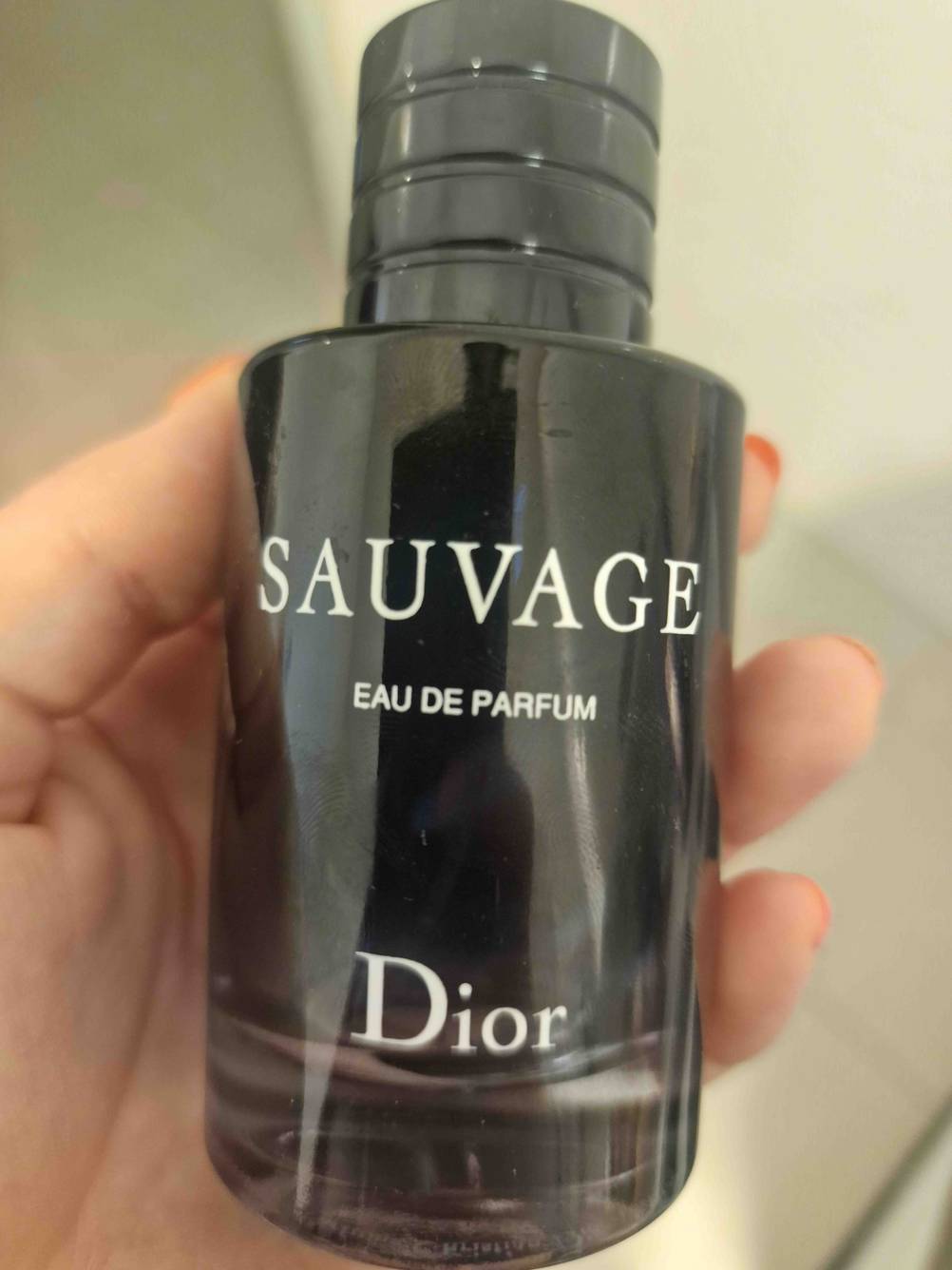 Nahaufnahme einer Hand die eine Flasche des getesteten Parfums für Herren hält.