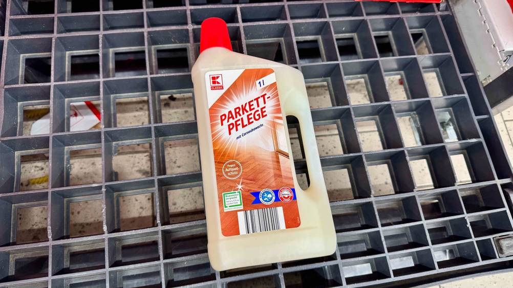 Parkettpflege getestet: Eine Flasche von schräg oben auf einem Plastikgitter liegend.