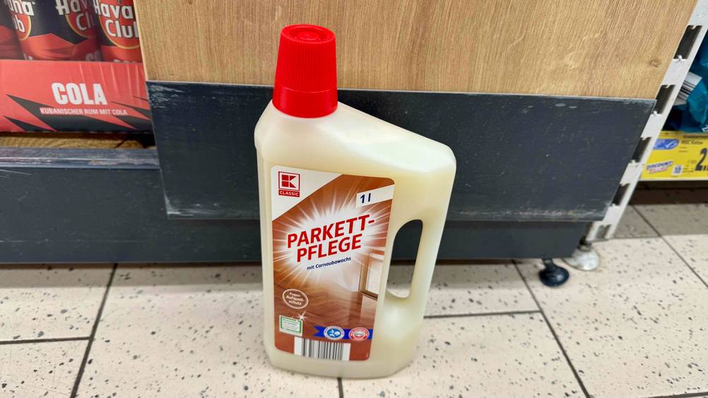 Parkettpflege im Test: Eine Flaschen von schräg oben vor einem Regal.