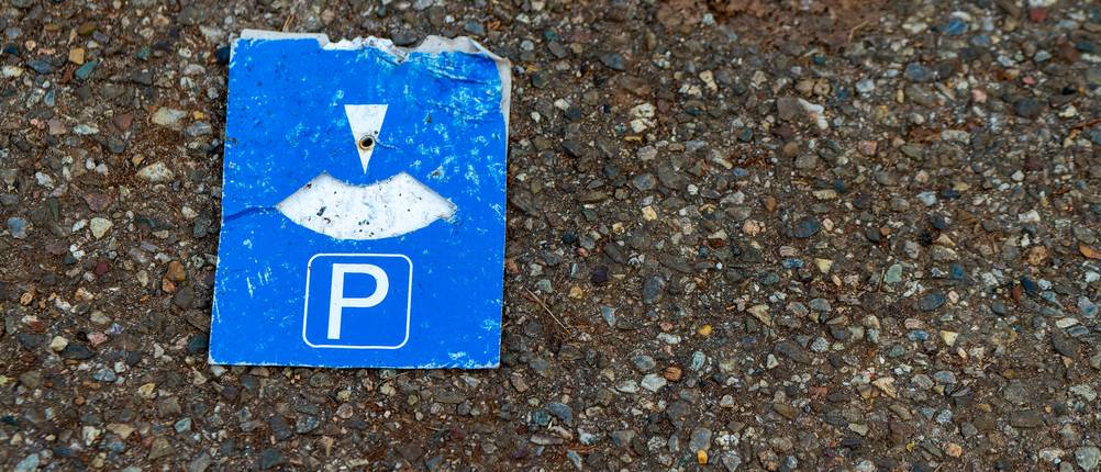 Parkscheiben-Test: eine alte unbrauchbare Parkscheibe liegt auf dem Asphaltboden