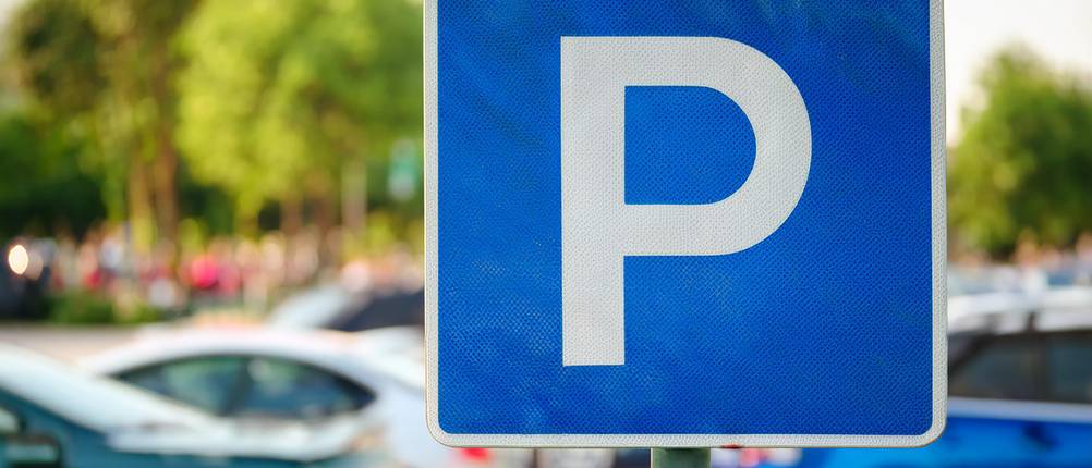 Parkscheiben-Test: typisches Parkplatz-Verkehrszeichen auf einem Parkplatz, im Hintergrund Autos 