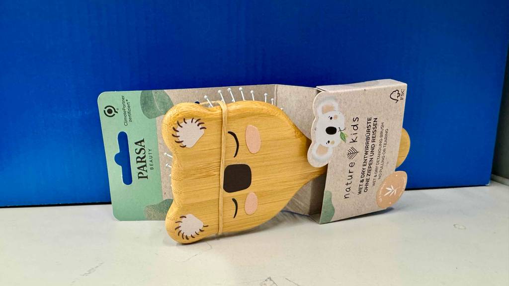 Im Test: Eine Babybürste mit Entwirrborsten liegt innerhalb der Verpackung vor einem blauen Hintergrund.