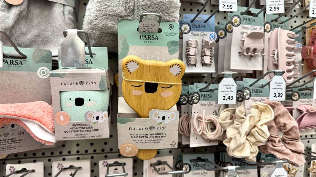 Eine getestete Babybürste mit Entwirrborsten hängt inklusive Verpackung an einem Verkaufsstand neben weiteren Artikeln der Marke Parsa.