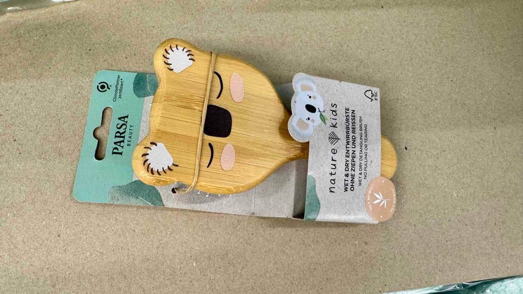 Getestet: Eine Babybürste mit Entwirrborsten liegt in der Verpackung auf einem beigefarbenen Untergrund.