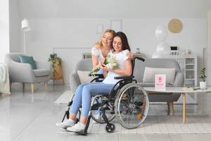 Partnersuche im Test: Eine Frau überreicht ihrer Freundin im Rollstuhl einen Strauss Blumen.