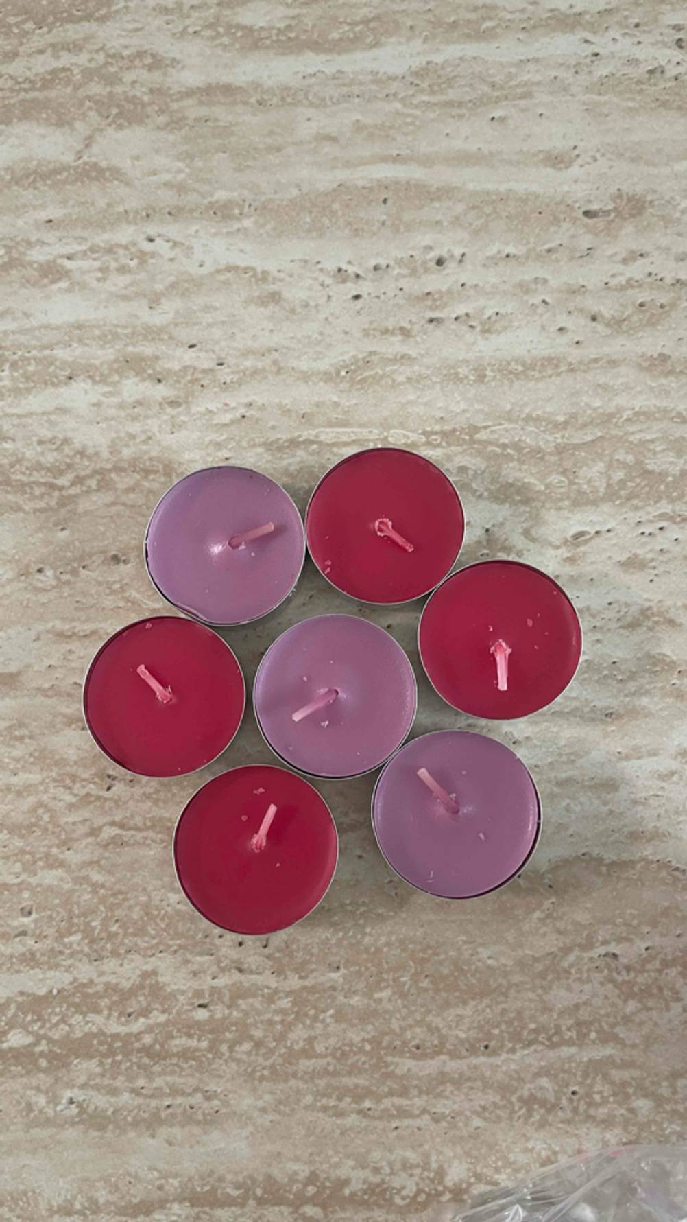 Partylite-Kerzen getestet: Malvenfarbige und rote Teelichter stehen als Blüte angeordnet auf einer braunen Oberfläche.
