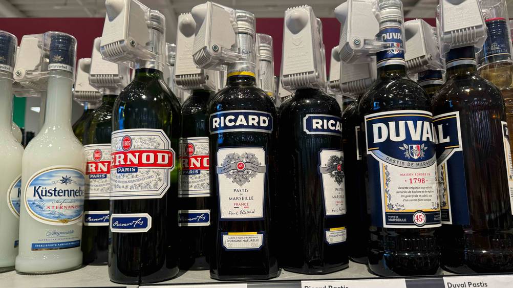 In einem Verkaufsregal stehen mehrere Flaschen des getesteten Pastis neben anderen Produkten.