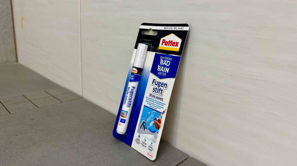 Getestet: Ein verpackter Fugenstift lehnt an Fliesen.