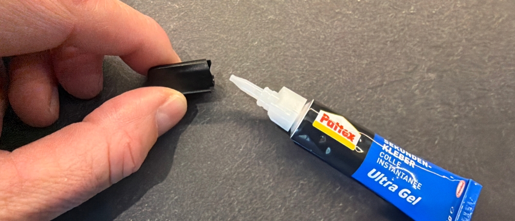 Eine Hand entfernt die Kappe vom Pattex-Sekundenkleber-Ultra-Gel