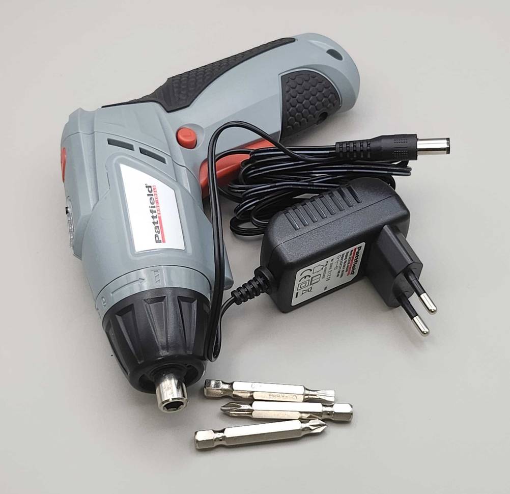 Ein bürstenloser Akkuschrauber im Test liegt inklusive Zubehör auf einer hellgrauen Oberfläche.