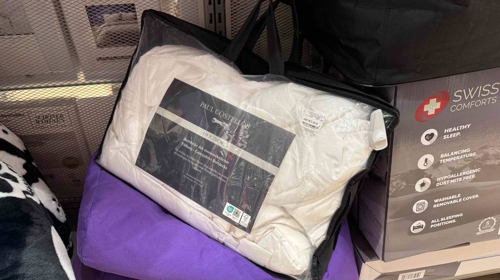 Eine verpackte Bettdecke 155x200 steht zum testen in einem Regal.