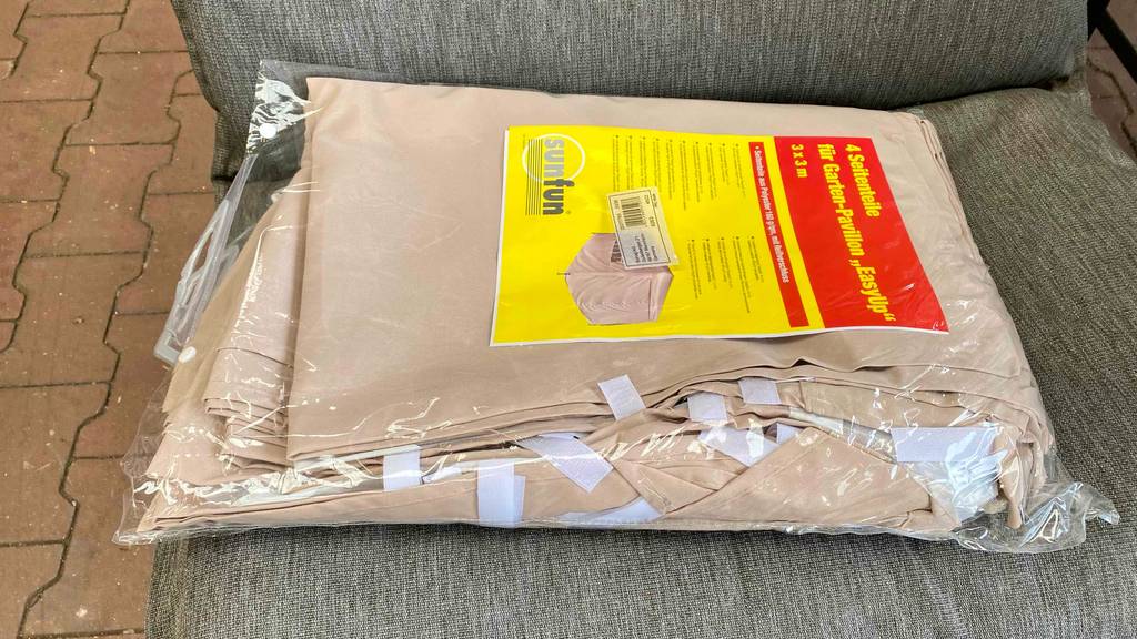 Ein getesteter Pavillon liegt verpackt auf einem Gartenstuhl. 