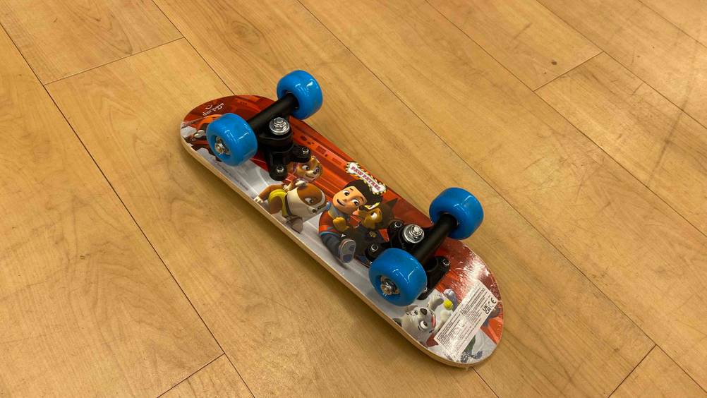 Im Test: Paw Patrol Skateboard für Kinder liegt mit den Rollen nach oben auf Holzboden.