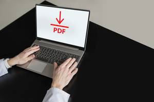 PDF-Editoren im Test: Eine Person lädt an ihrem Laptop eine PDF-Datei herunter.