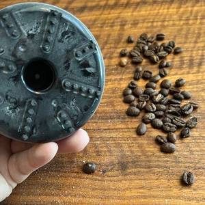 Verschmutzte Unterseite des Peach-PA105 sowie Kaffeebohnen auf dem Tisch.