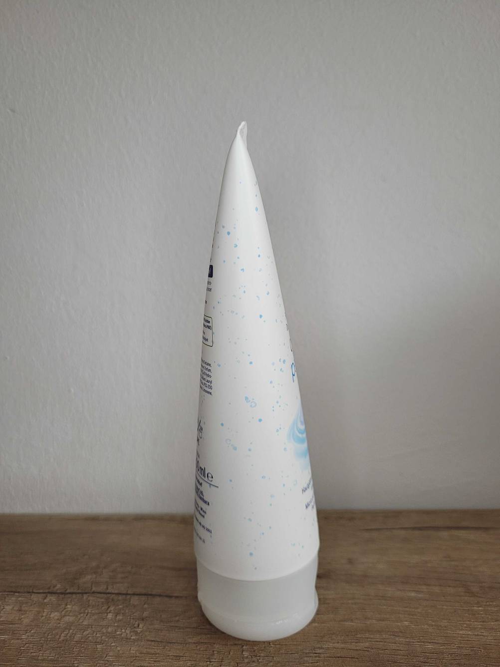 Getestet: Eine Tube Peeling von der Seite auf einer Holzfläche vor einer hellen Wand.