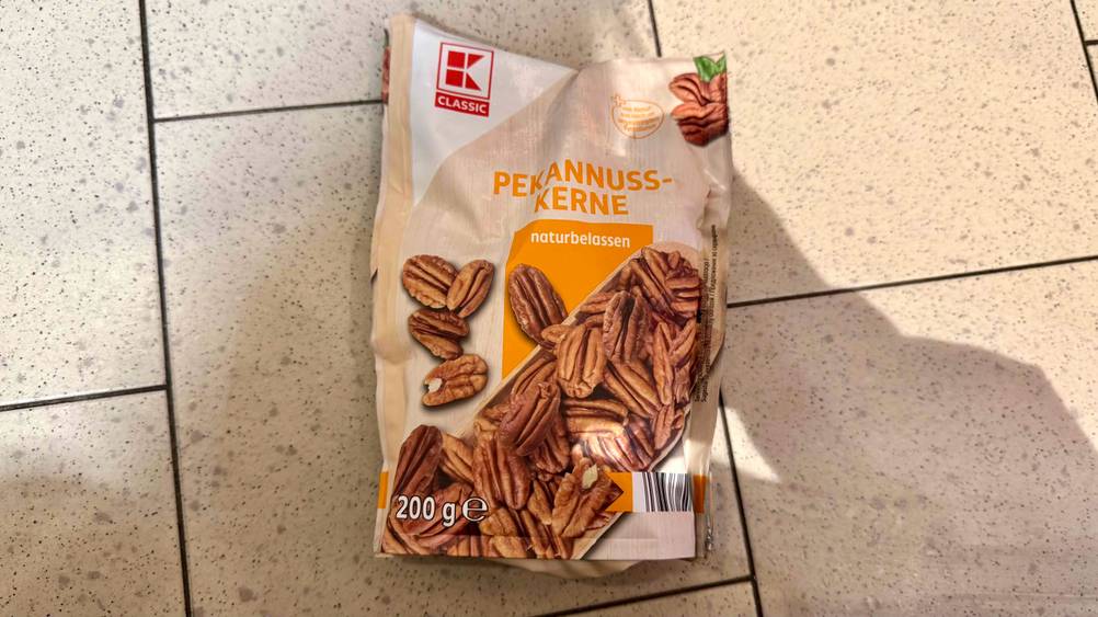 Getestet: Eine Packung Pekannüsse von oben auf einem Fließenboden liegend.