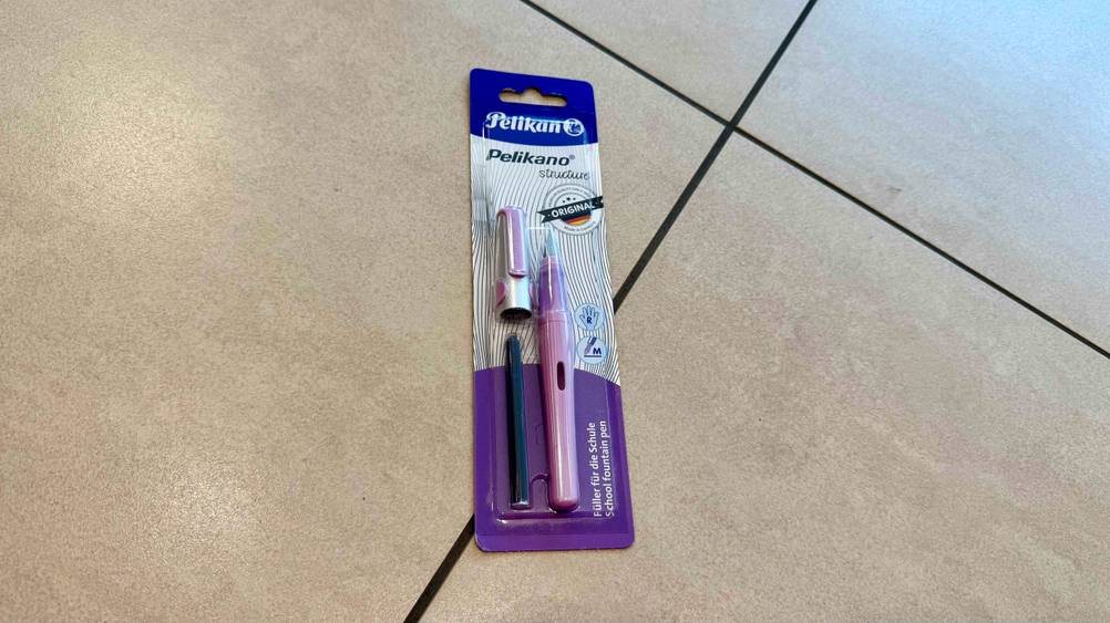 Auf einem Fließenboden liegt ein Pelikan-Füller im Test in seiner Originalverpackung.