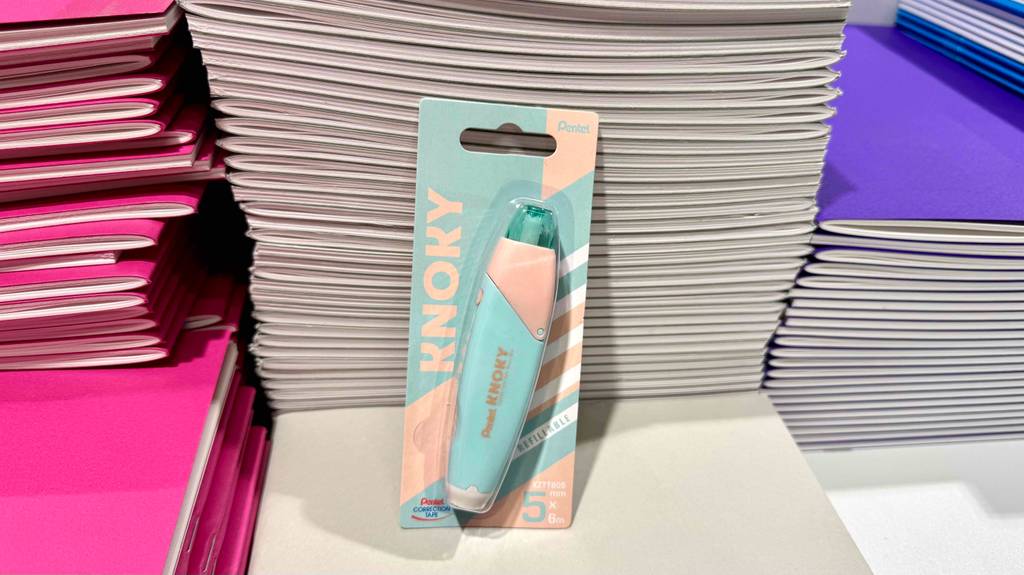 Der nachfüllbare Korrekturroller im Test befindet sich in einer Verpackung auf einem Verkaufsregal vor bunten DIN-A4-Heften.