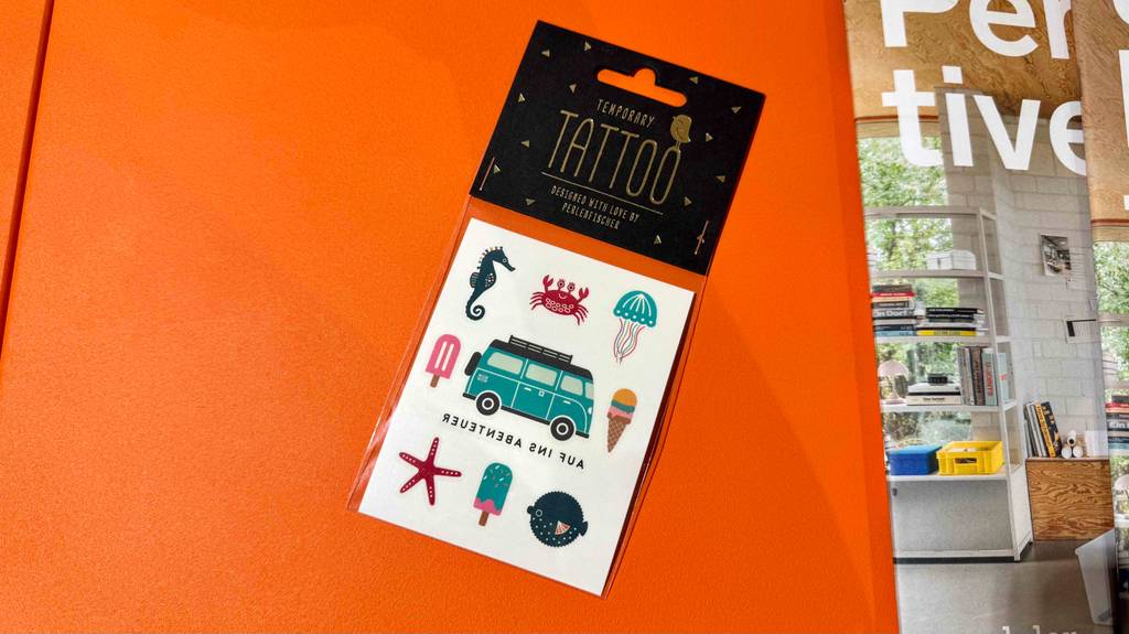 Neben einer Zeitschrift liegt die Verpackung mit getesteten temporären Tattoos.