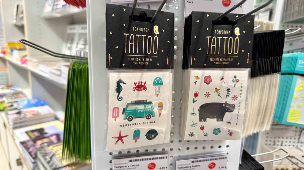 An einem Verkaufsregal hängen mehrere Verpackungen mit getesteten temporären Tattoos im Test.