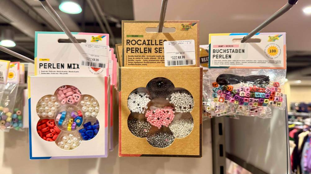 In einem Regal neben anderen Produkten hängt ein getestetes Perlenset.