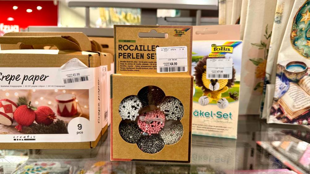 Auf einem Regal neben anderen Produkten steht ein Perlenset im Test.