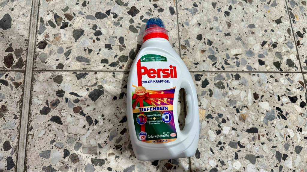 Eine Flasche getestetes Persil-Flüssigwaschmittel liegt auf einem gesprenkelten Fliesenboden.