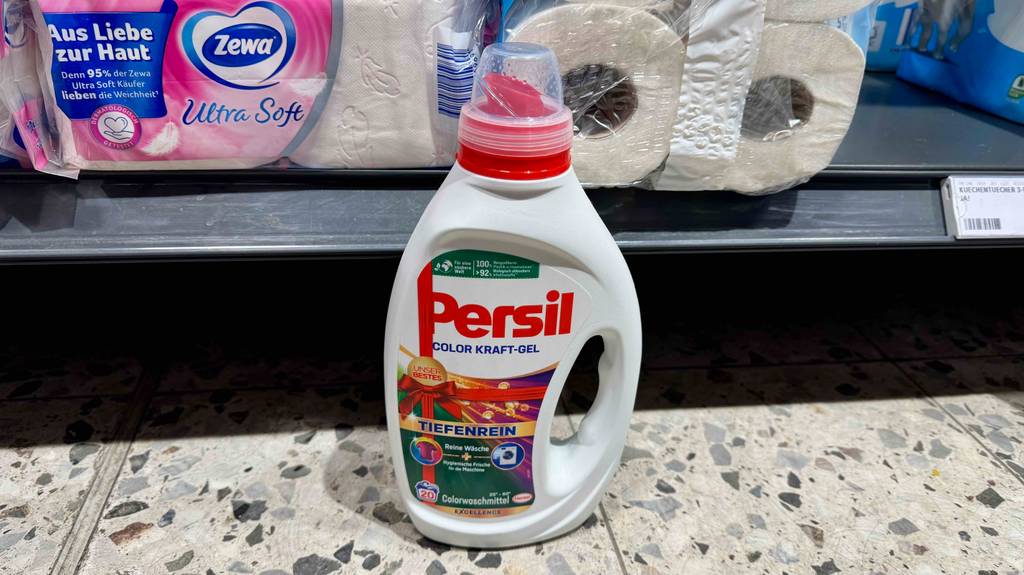 Eine Flasche Persil-Flüssigwaschmittel steht zum testen vor verpacktem WC-Papier.