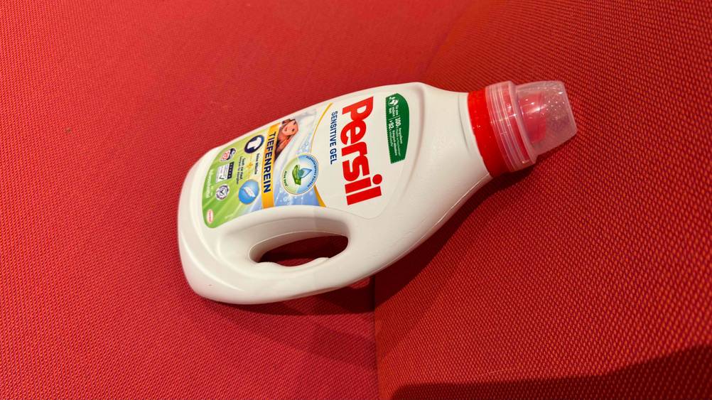 Eine Flasche des Persil-Waschmittel im Test von schräg oben auf einem roten Polster.