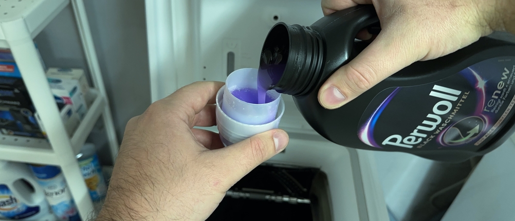 Das kräftig lilafarbene Waschmittel von Coral wird in die Verschlusskappe gefüllt.