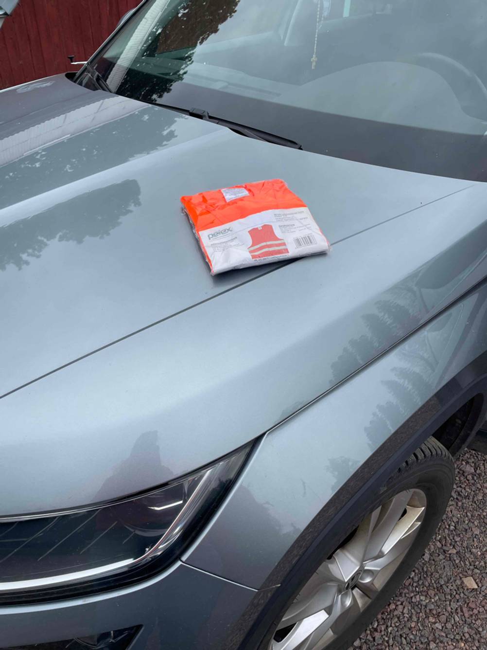 Im Test: Auf einer Motorhaube liegt eine verpackte Warnweste.
