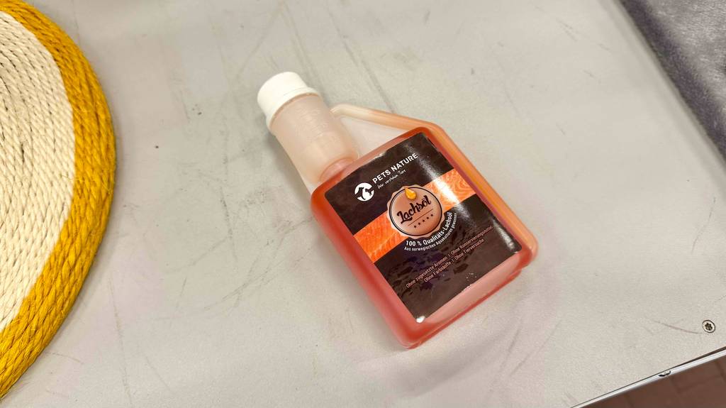 Lachsöl für Hunde im Test: Eine Kunststoffflasche mit Dosierkappe liegt auf dem Boden.