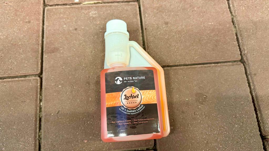 Getestet: Lachsöl für Hunde in der Kunststoffflasche mit Dosierkappe liegt auf einem Fliesenbelag.