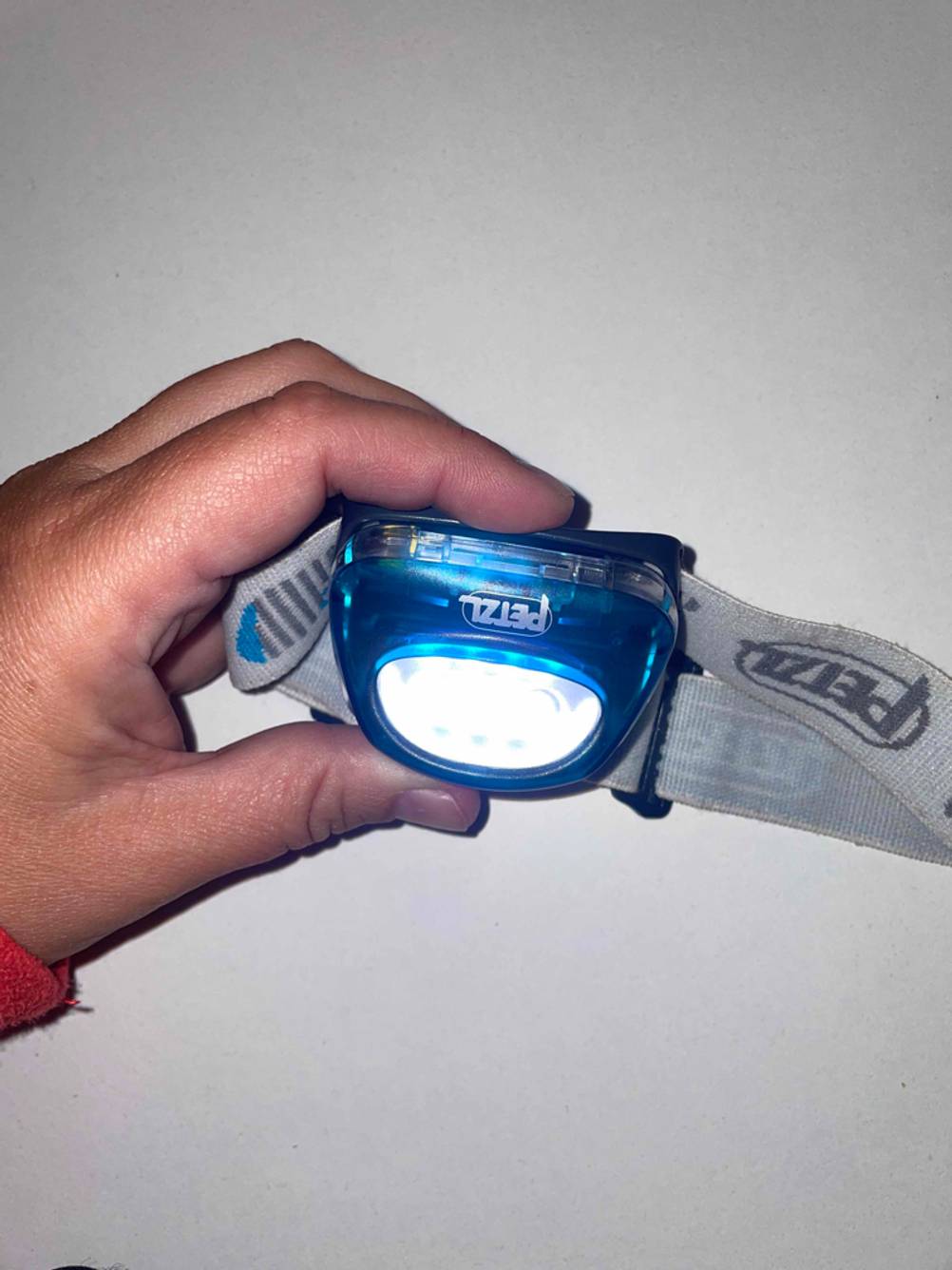 Petzl-Stirnlampen-Test: Eine Hand hält eine angeschaltene Petzl-Stirnlampe.