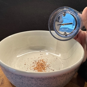 Unterseite der Peugeot-Muskatmühle Goa und gemahlene Muskatnuss in einer Schale