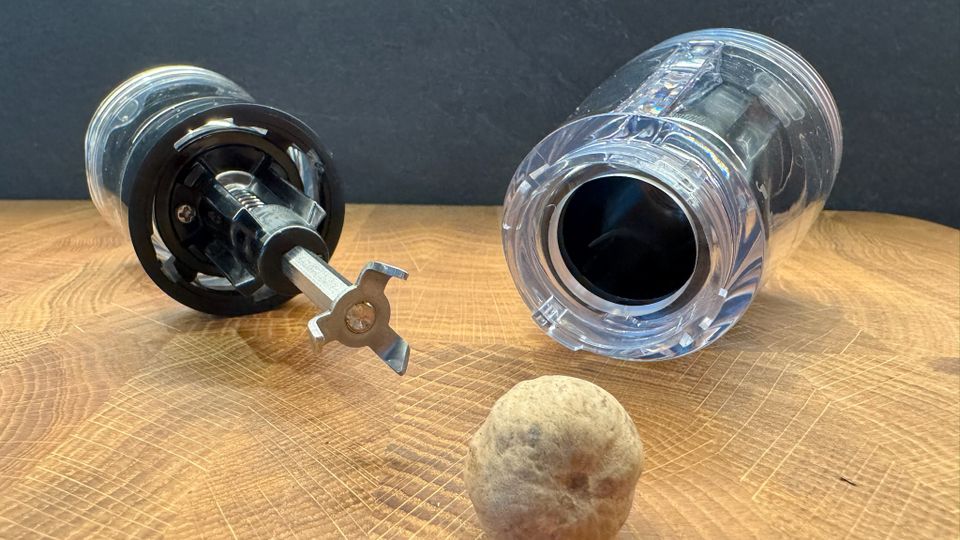 Peugeot-Muskatmühle Goa liegt mit einer einzelnen Muskatnuss auf einem Holzbrett