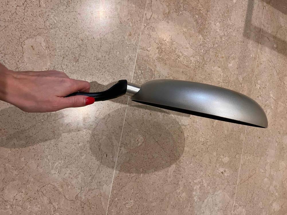 Eine Hand hält eine getestete Pfanne mit 24 cm Durchmesser. 